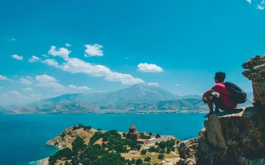 A man with travel gear to a tub on the edge of a cliff