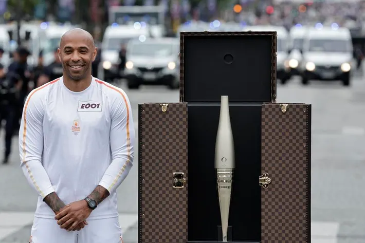 The legend of French football, Thierry Henry, next to the casket holding the Olympic torch and the torch