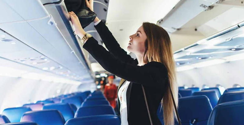 Placing a handbag in an airplane compartme, photo source: onmanorama, photographer: unknown