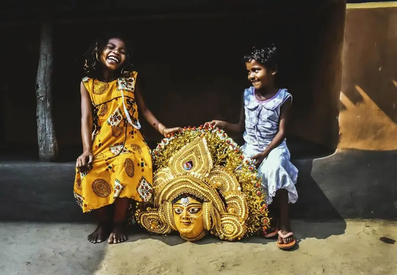 Two village children in India next to a golden statue