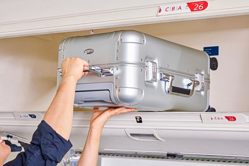 placing the size cabin luggage in the cabin compartme of the plane; Photo source: Travel + Leisure website. Photographer: Unknown
