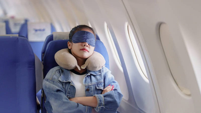 Tourist sleeping with a neck pillow and blindfold in the airplane seat, photo source: NBC news website, photographer: unknown