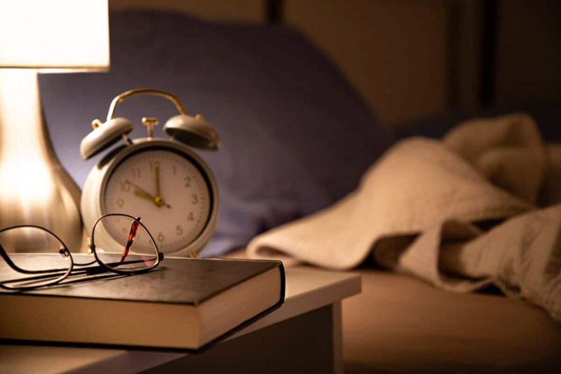 old alarm clock with book and glasses; Photo source: helpguide.org website; Photographer: Unknown