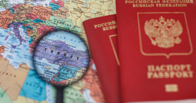 Russian passports and a map of Europe and a magnifying glass on the map of Türkiye; Photo Source: Aalya Tourist Information, Photographer: Unknown