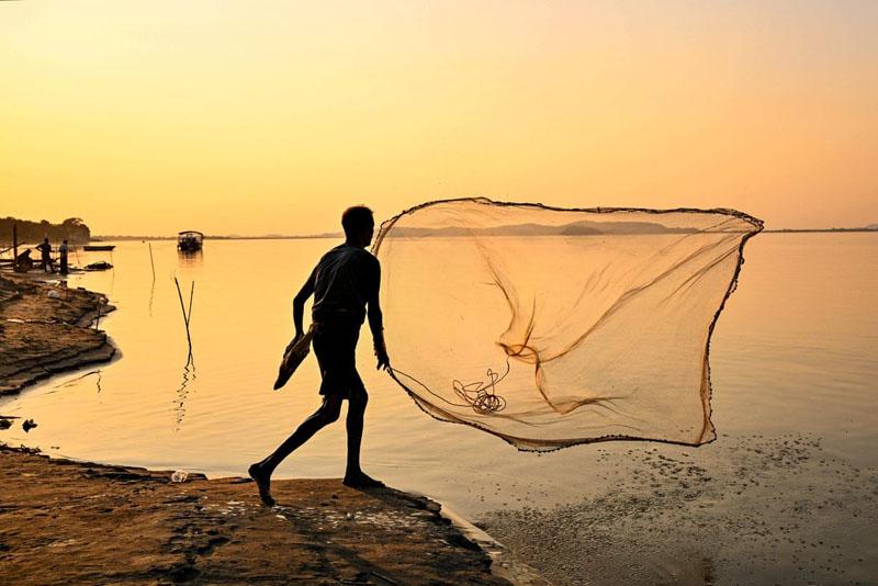 Indian fisherman on the banks of the Brahmaputra river at sunset; Photographer: Biju Boro 