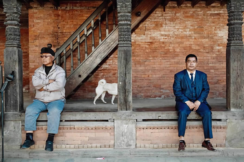Two men sitting next to a building