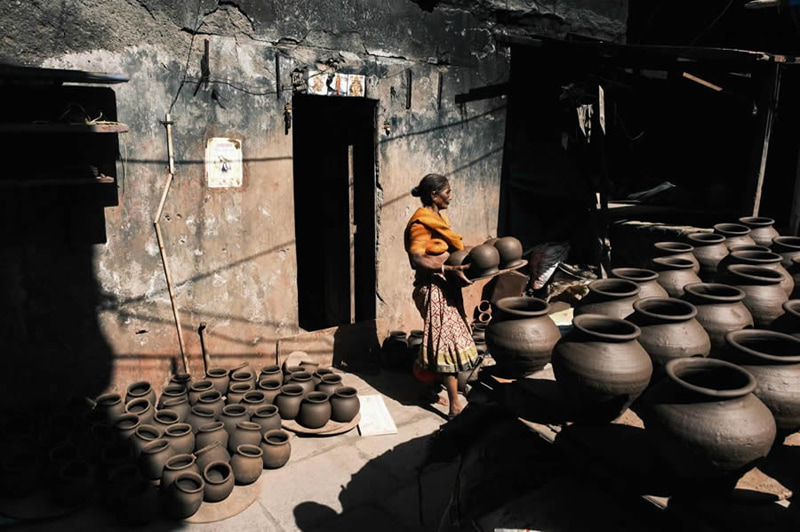 Asian woman carrying a clay jar