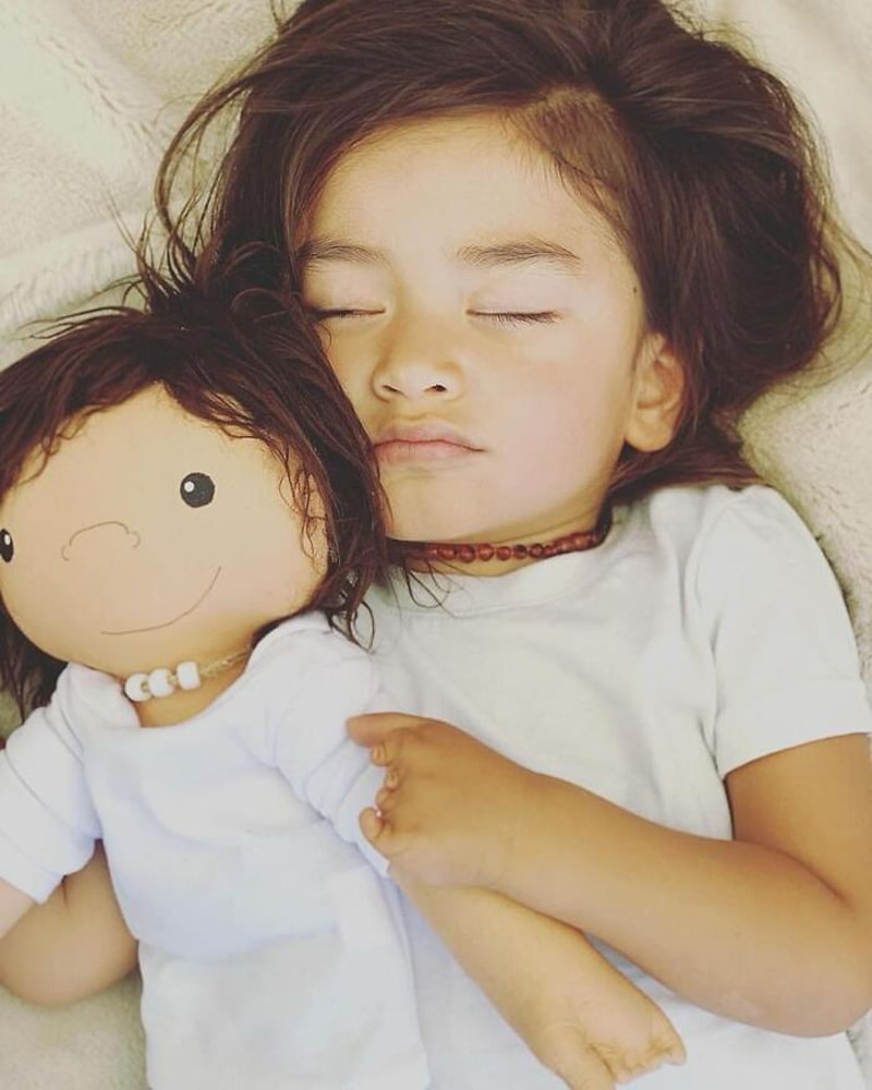 A girl sleeping next to her doll