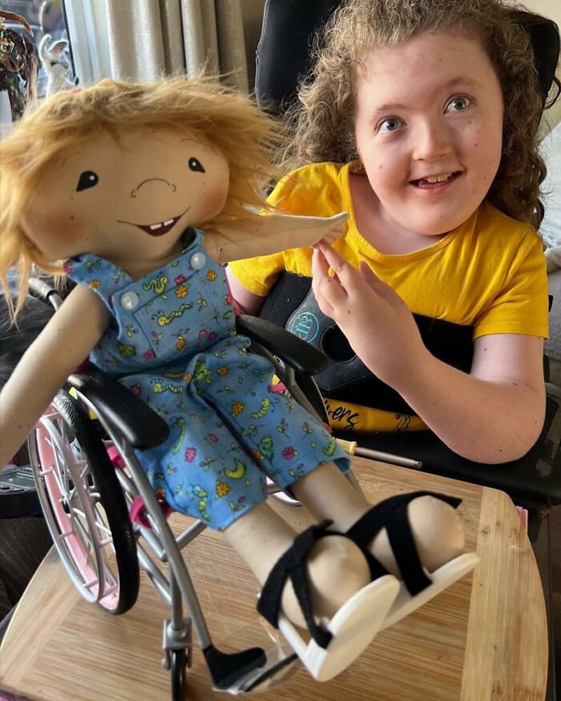 A little girl with a doll in a wheelchair