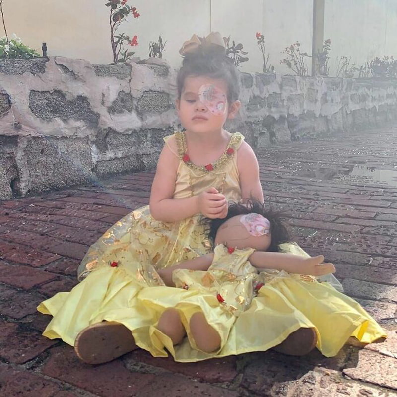A girl and a doll in a yellow dress