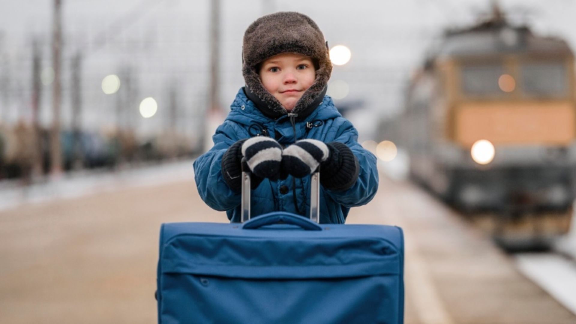 Children with wier clothing next to blue suitcase