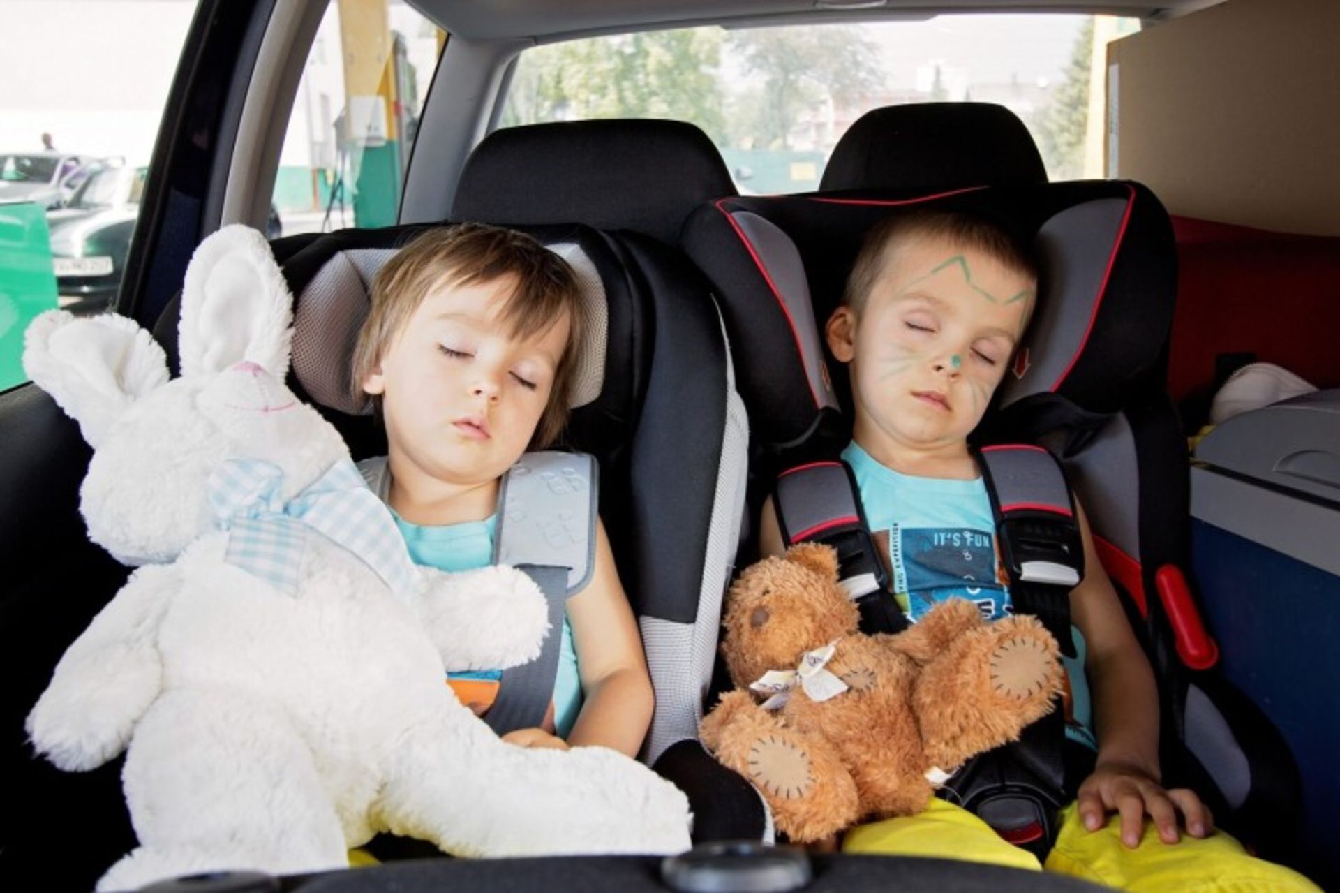 Two children sleeping in a special seat in the car