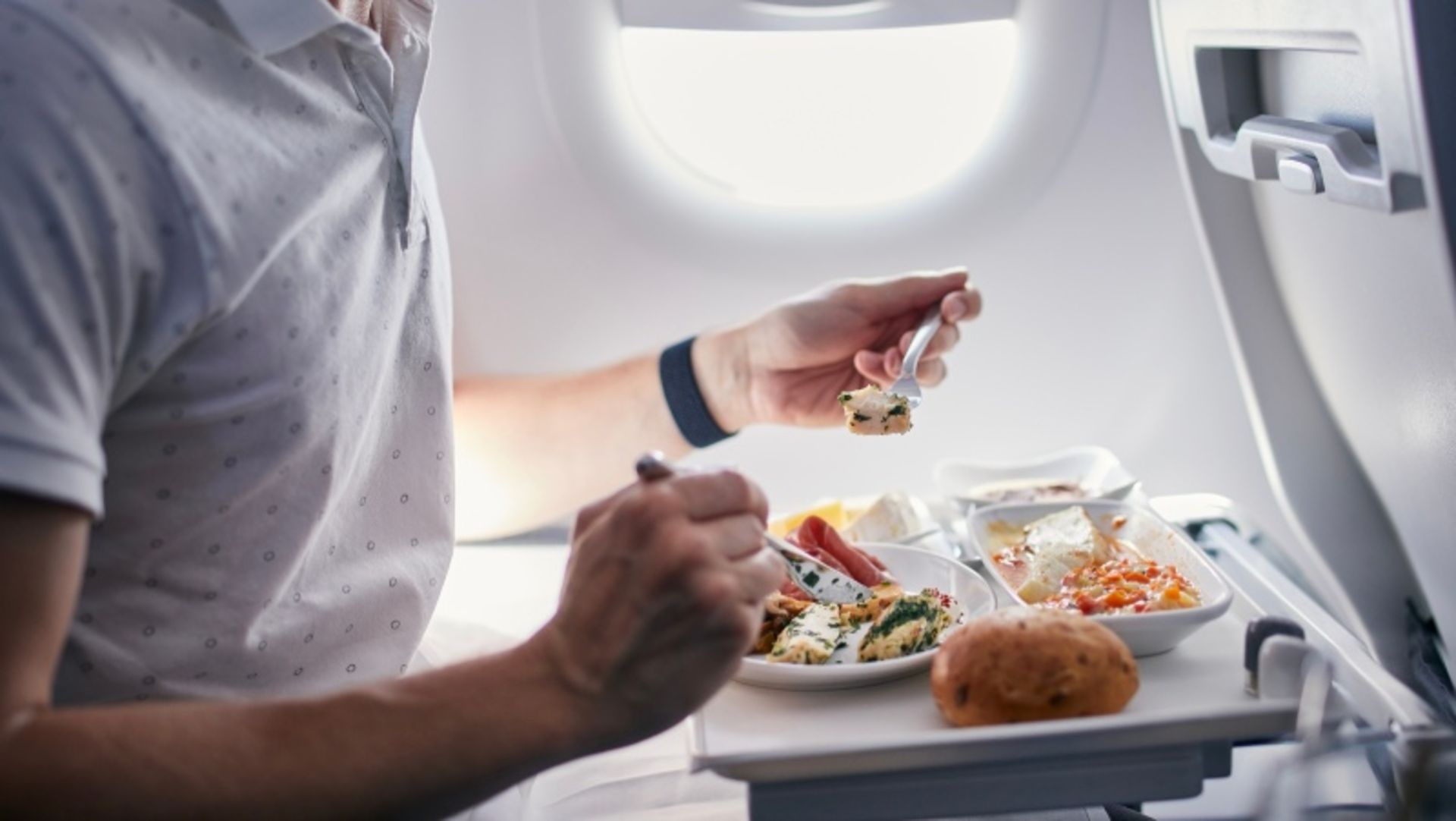 A man who is eating food on the plane