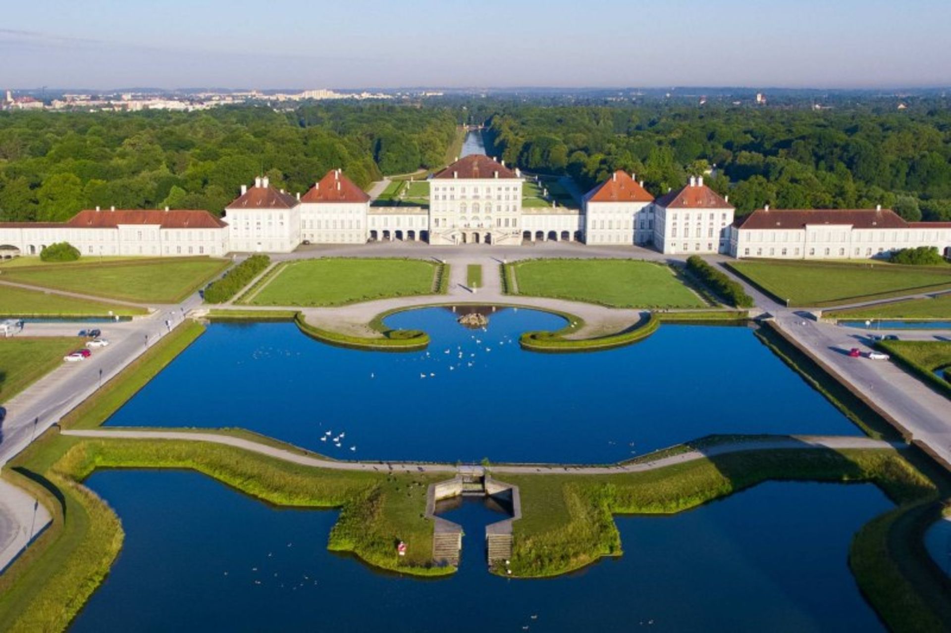 Nimfenburg Palace with white, trees and grass and water pool