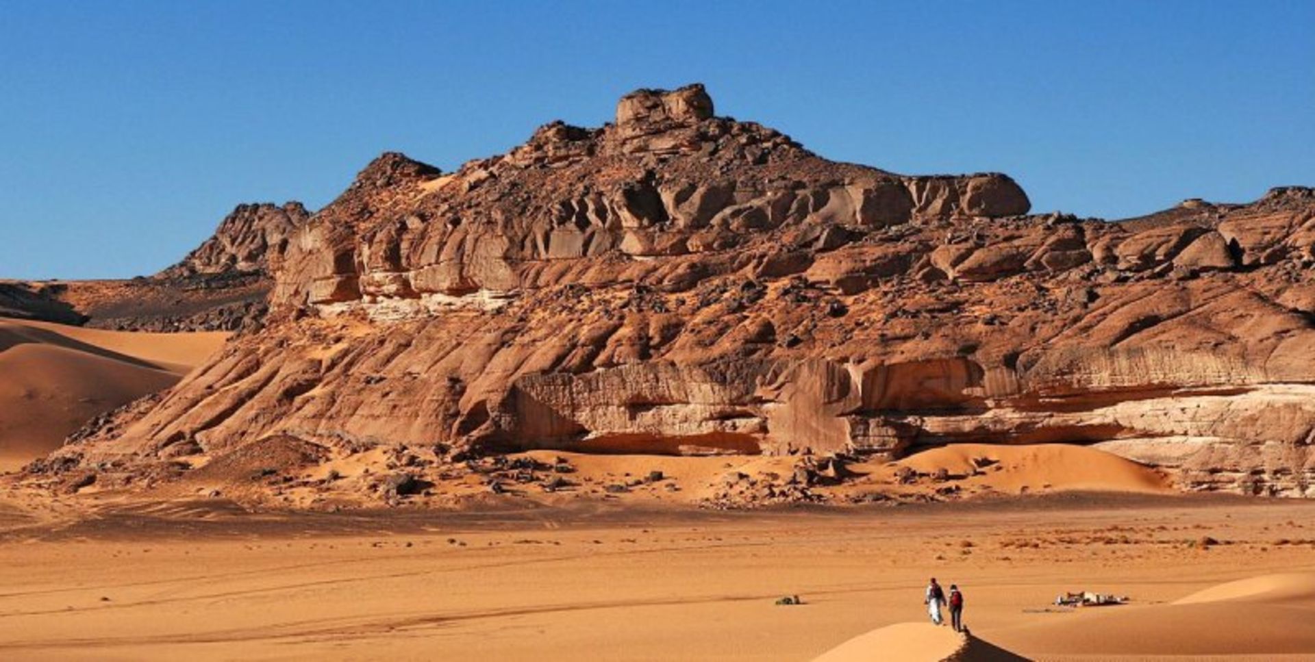 Sands, mouains, flat and blue sky and two people in the desert desert
