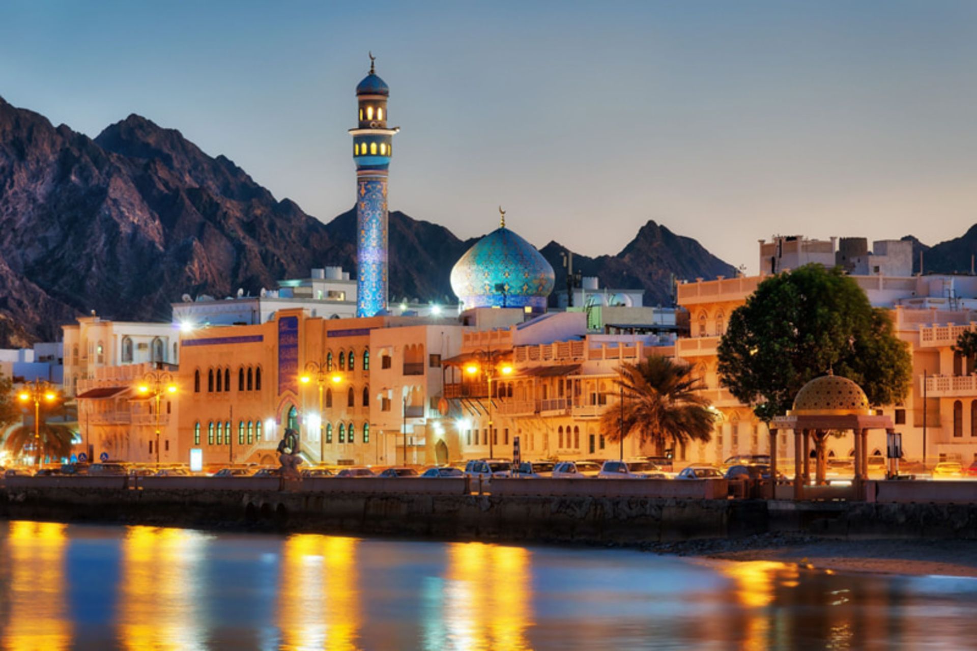 Oman Muscat City at sunset with mosque minarets, green dome and background mouains
