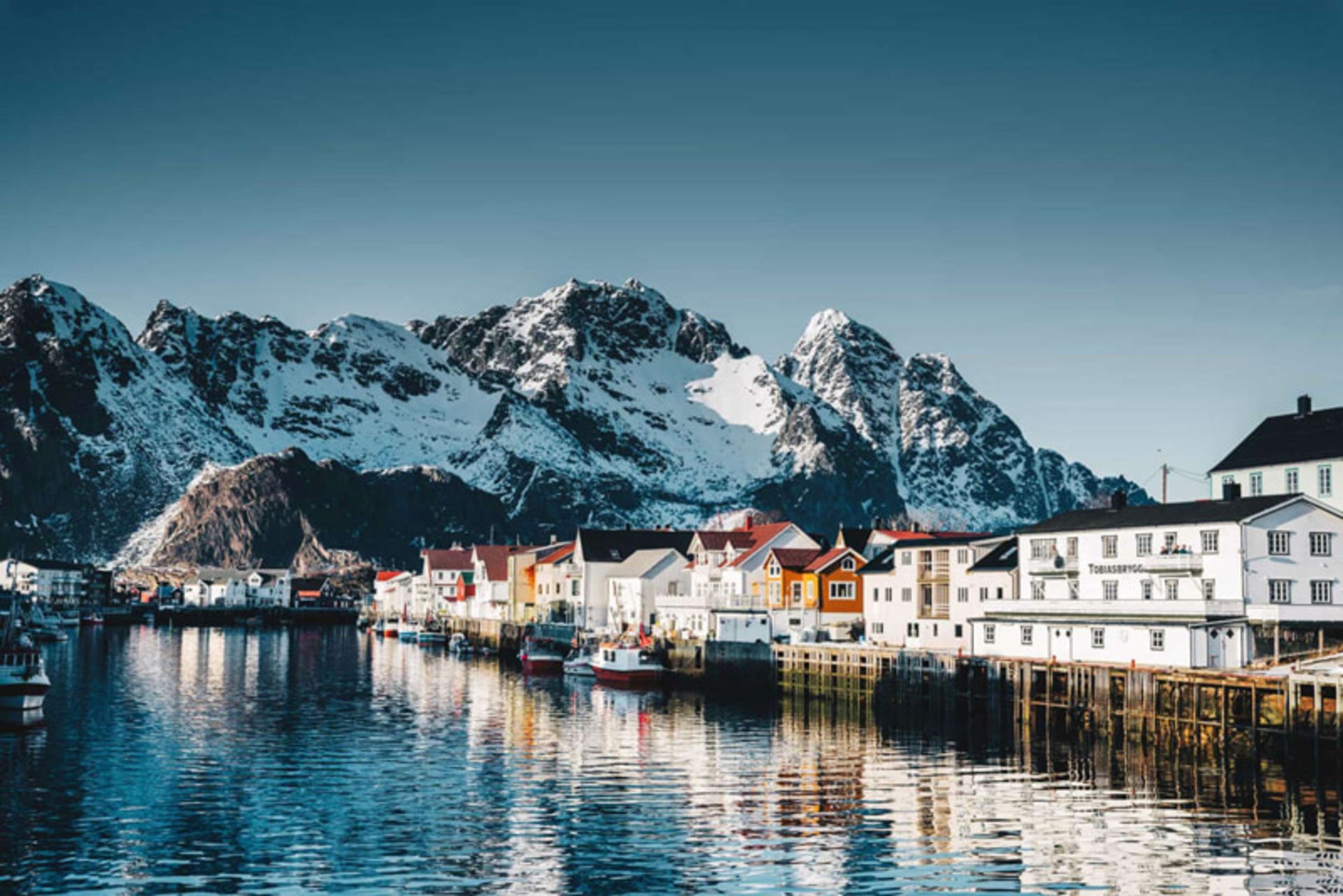 A beach village in Norway with colorful houses and snowy mouains
