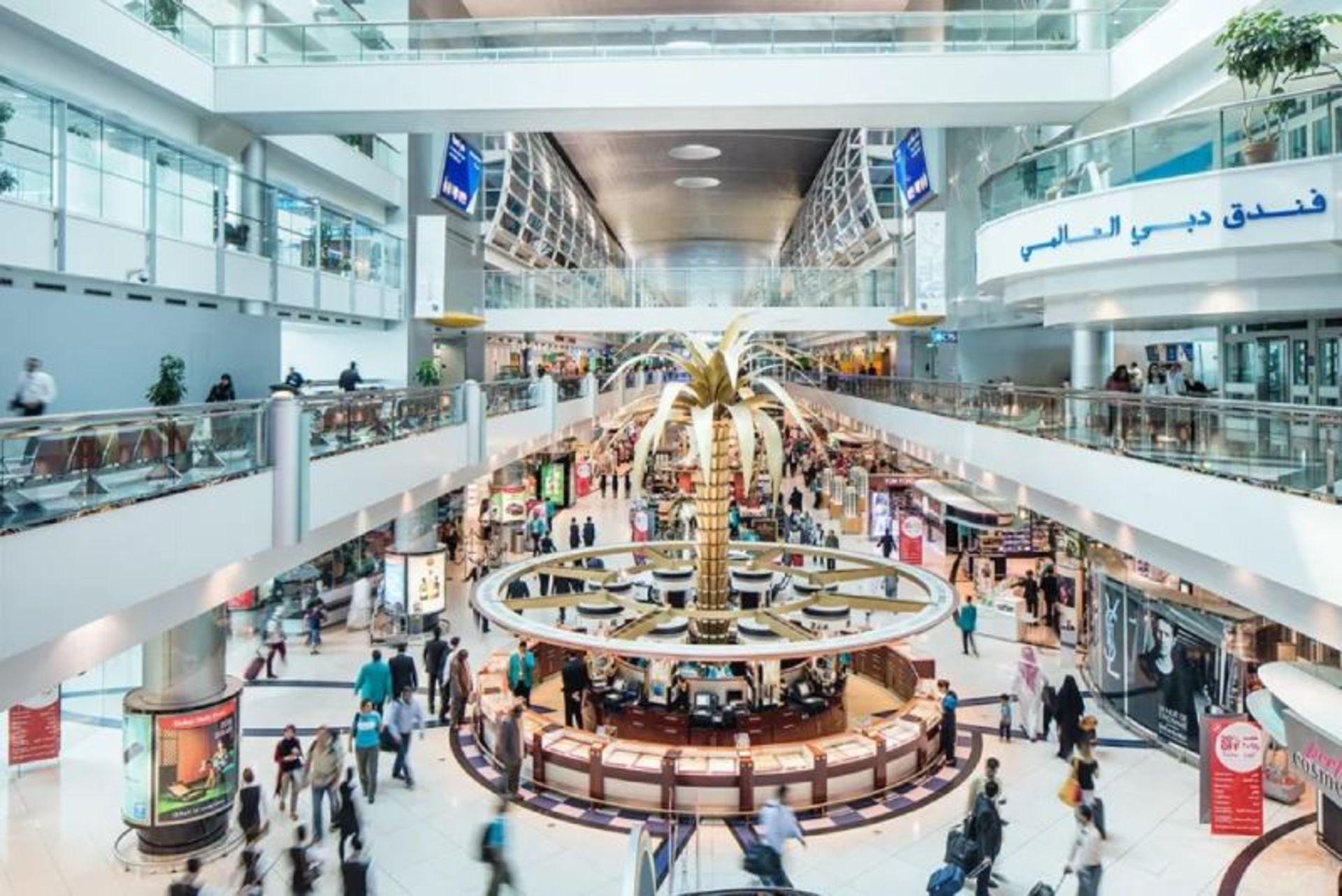 Golden Palm statue and passengers indoors Dubai Iernational Airport 