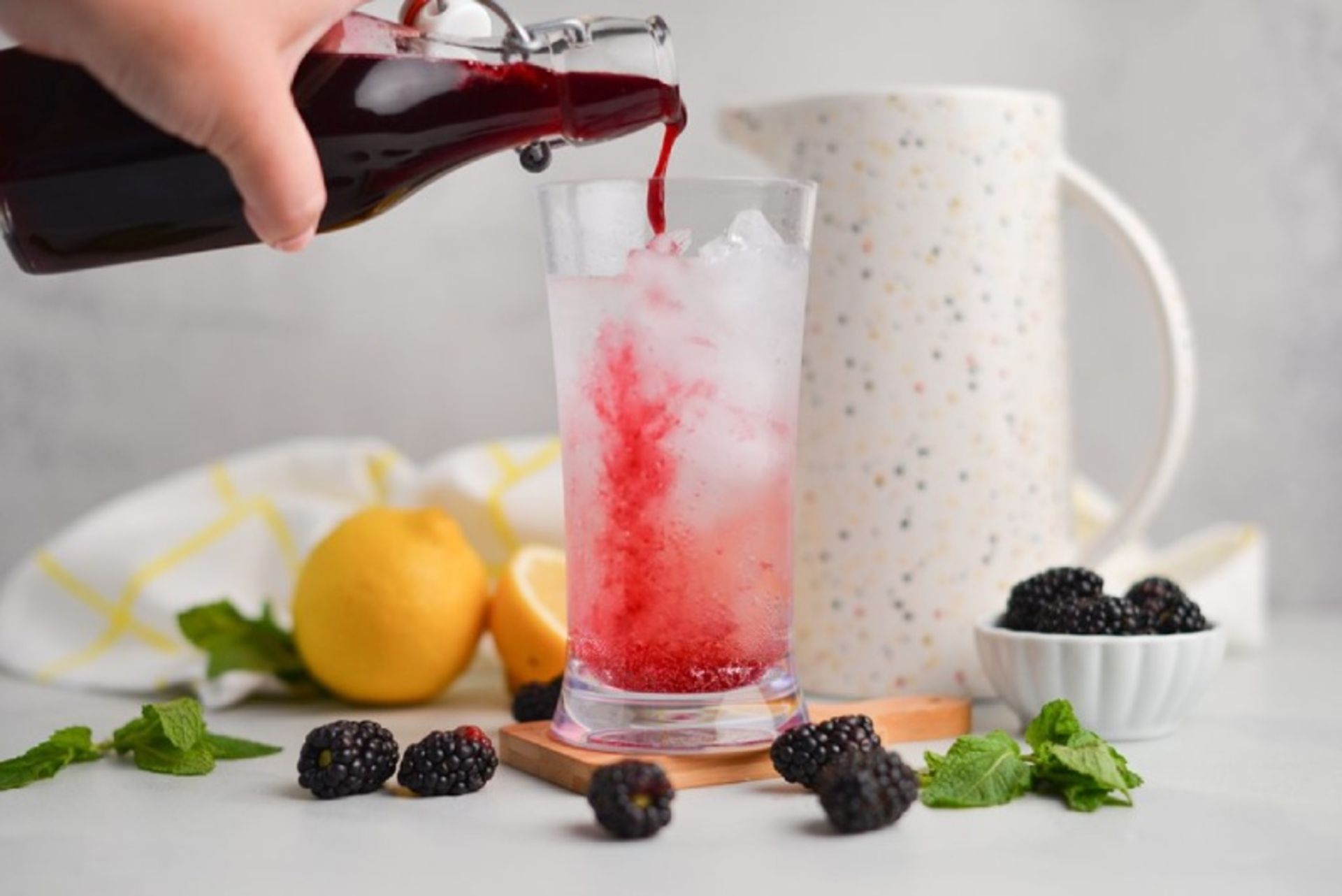 Pouring up blackberry syrup in the glasses of ice