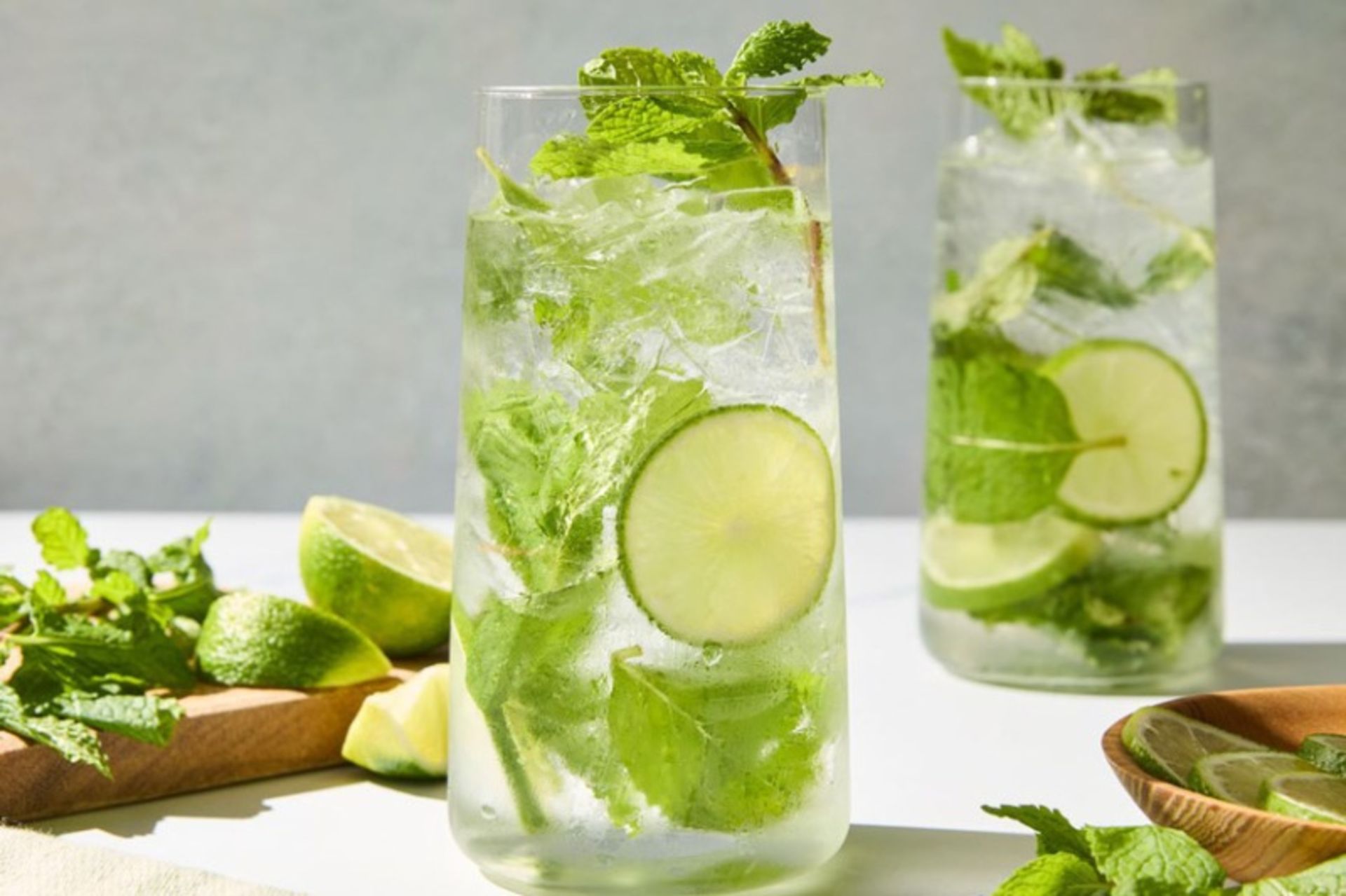 Two glasses of classic Mohito next to the mi leaf and lemons