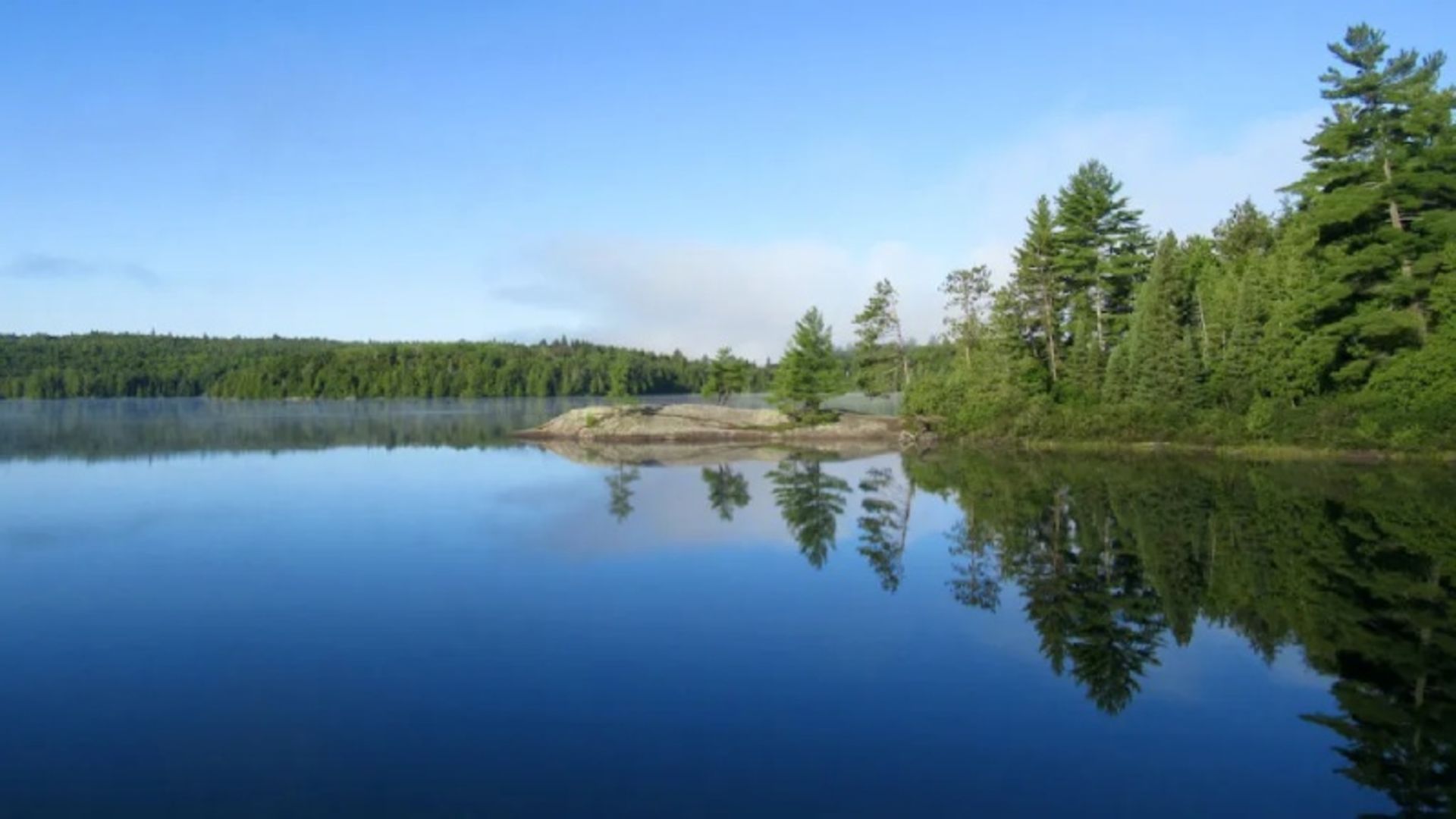 Reflection of trees and blue sky on Lake Rock in Oario