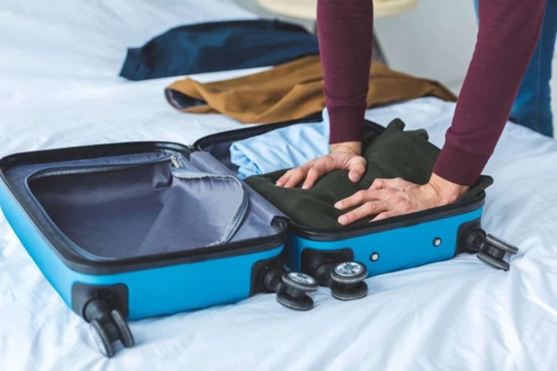 A man putting clothes inside the suitcase