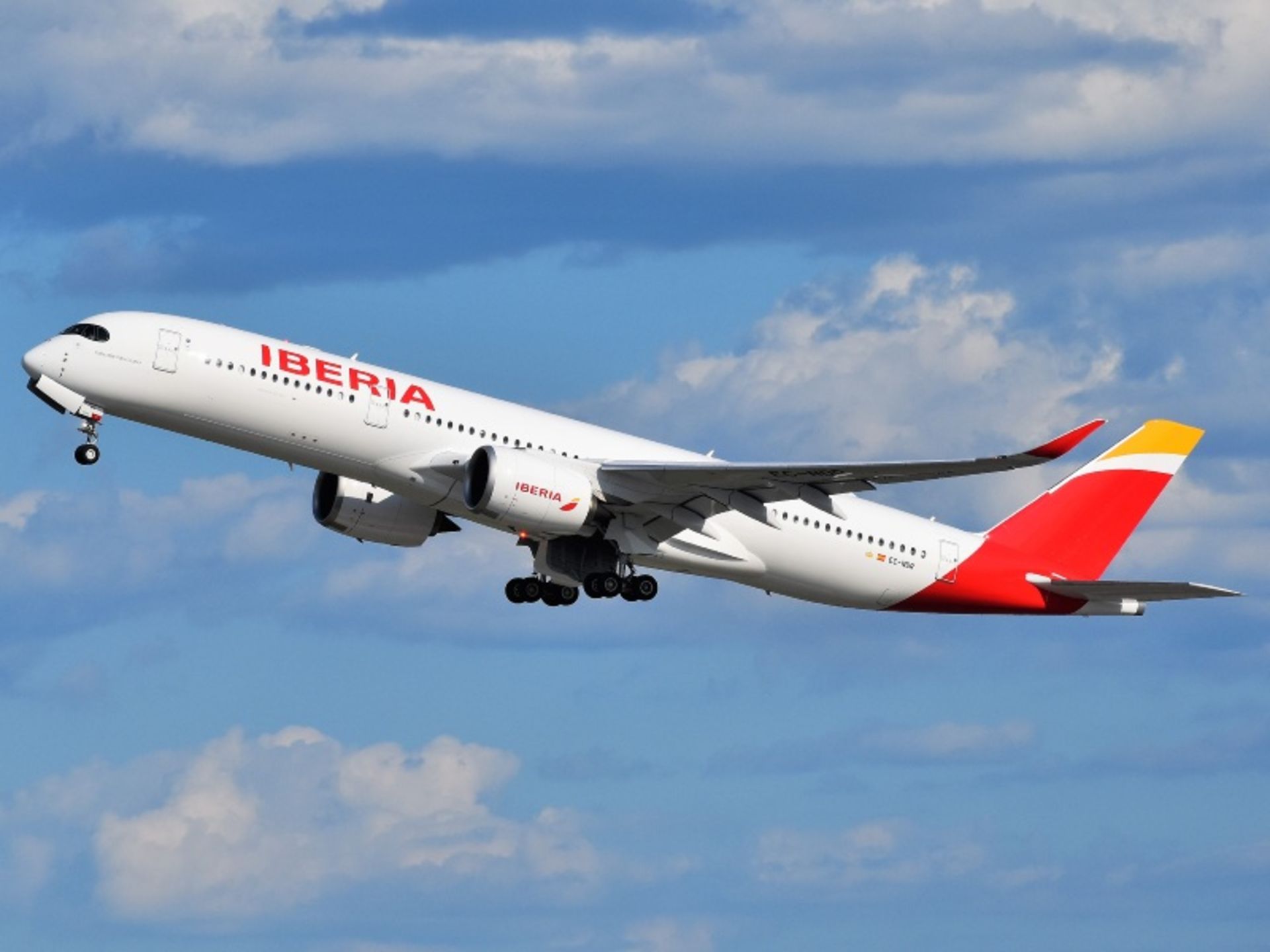Iberia Airlines aircraft in the blue sky between clouds