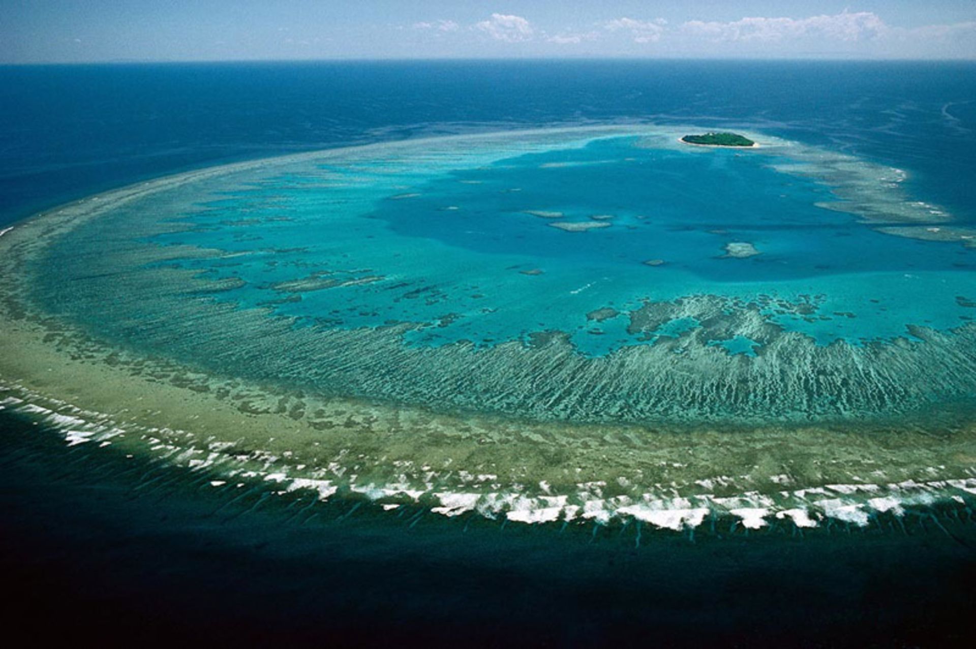 Great coral reef with turquoise waters and a small island in dista