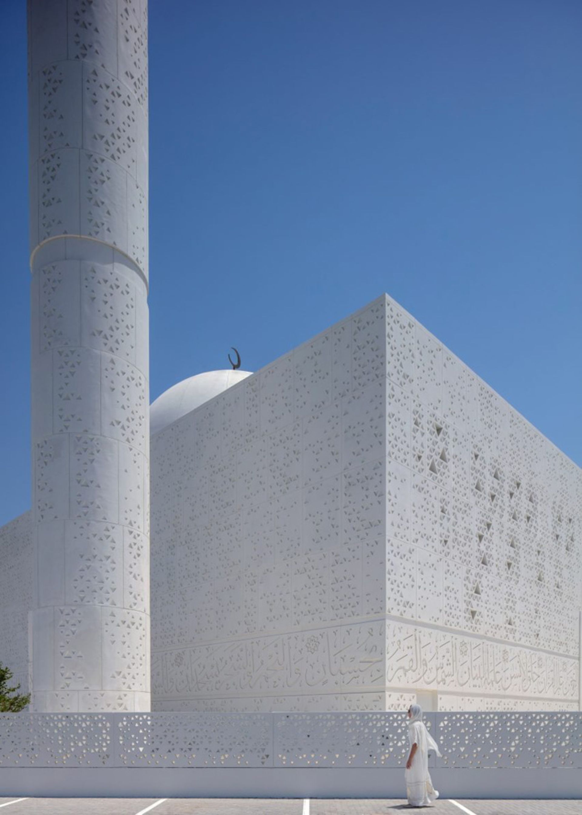 A woman passing by the white building of the Muhammad Abdul Khaliq Gargash Mosque in the UAE