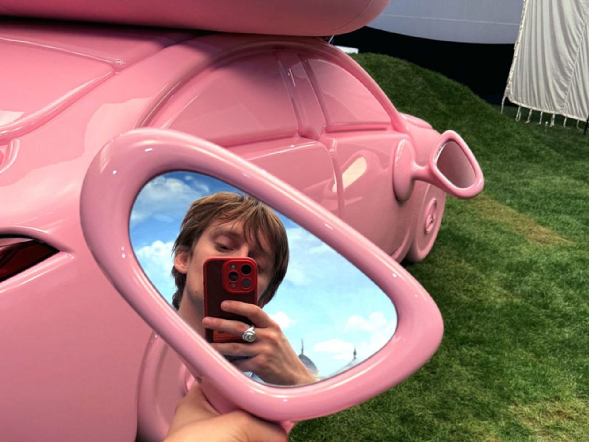 The image of a man in the mirror of a pink Mercedes-Benz for glamping