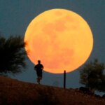 A runner traverses a hill course in front of a supermoon over Papago Park in Phoenix in May 2012.