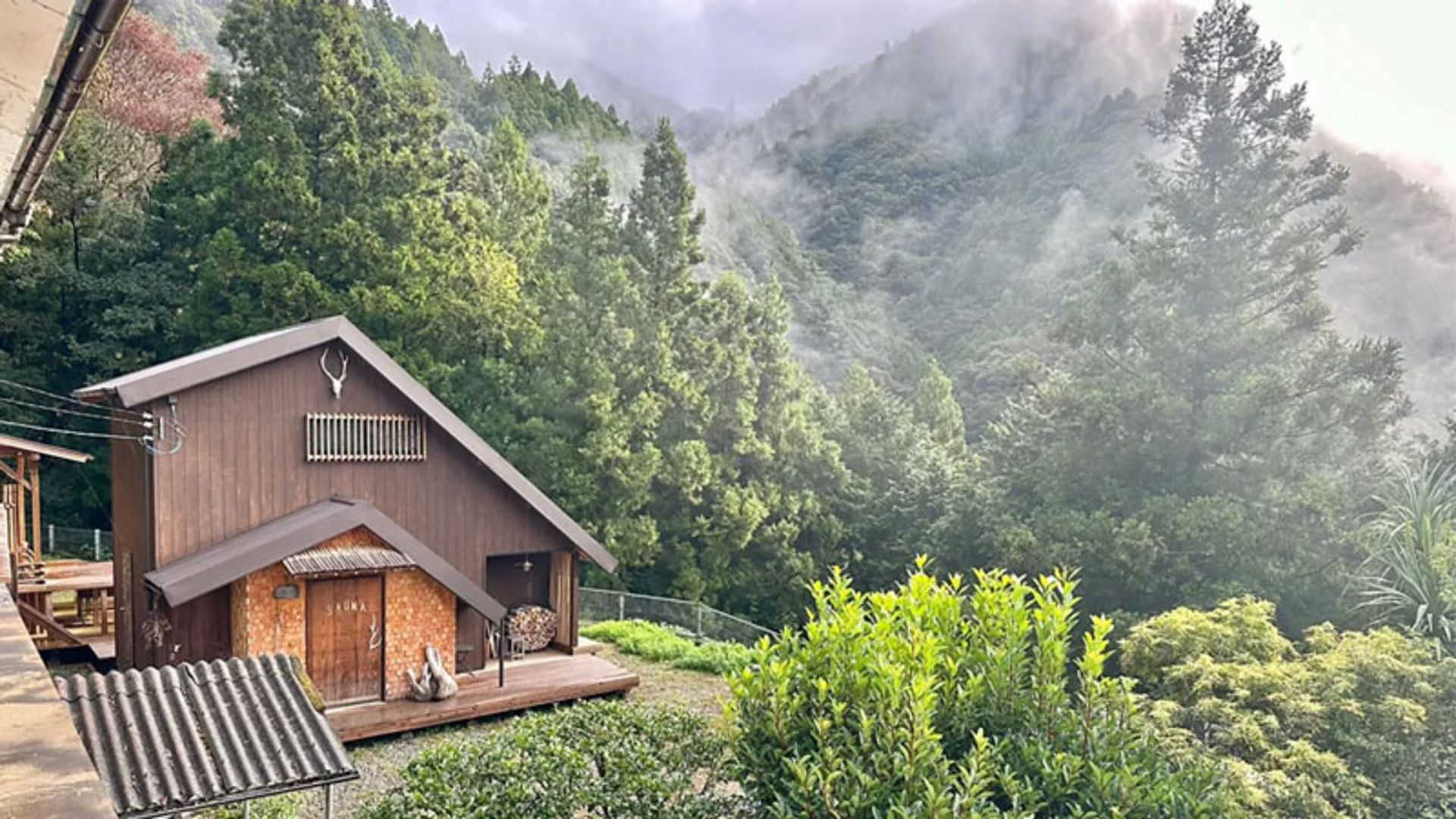 A log cabin with a terrace and a view of the dense Japanese mouain forests