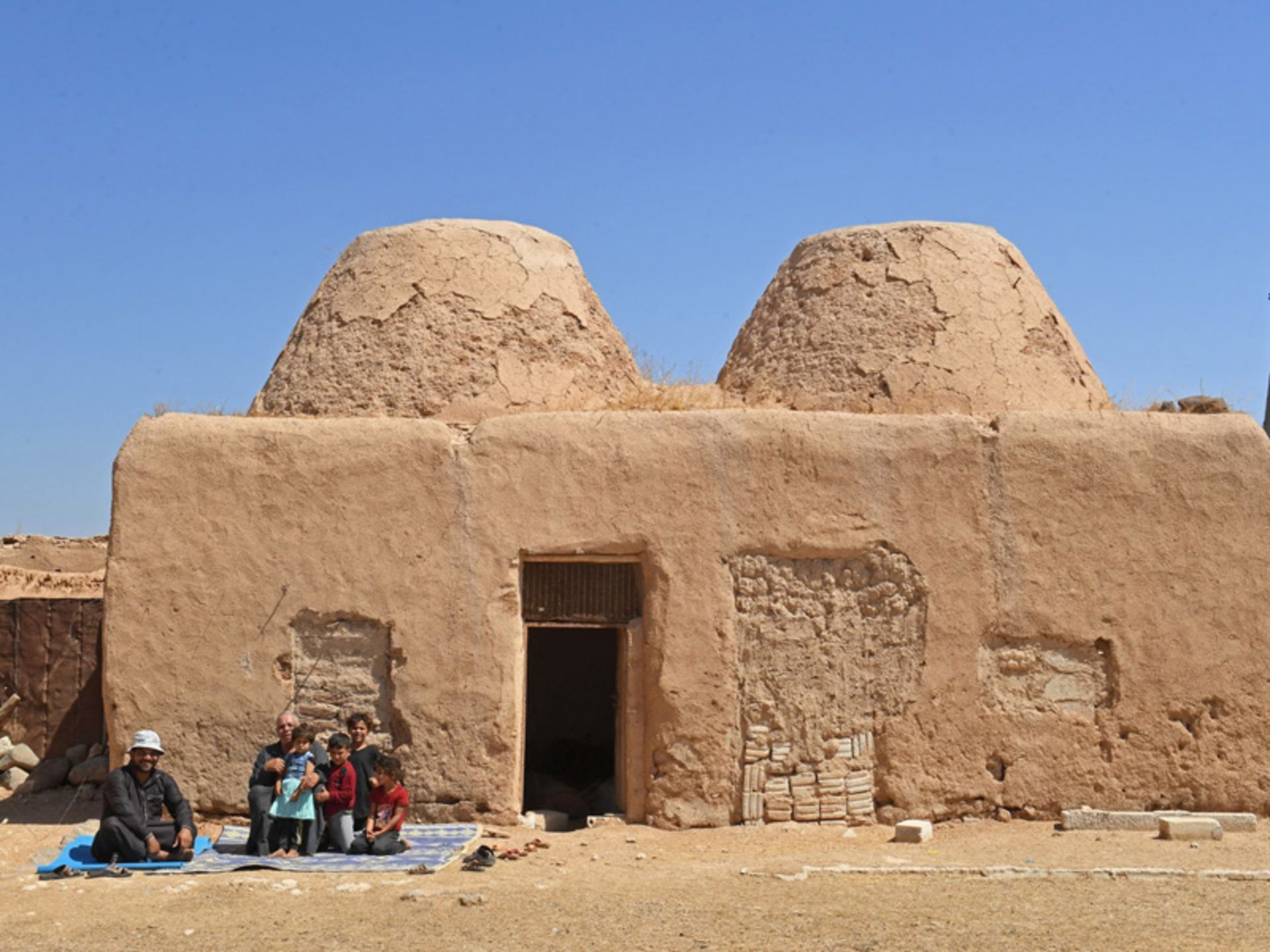 People next to mud houses in the desert city
