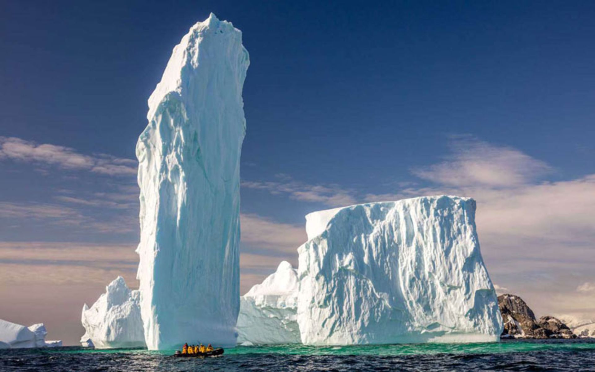 A small boat next to the gia ice columns of Aarctica