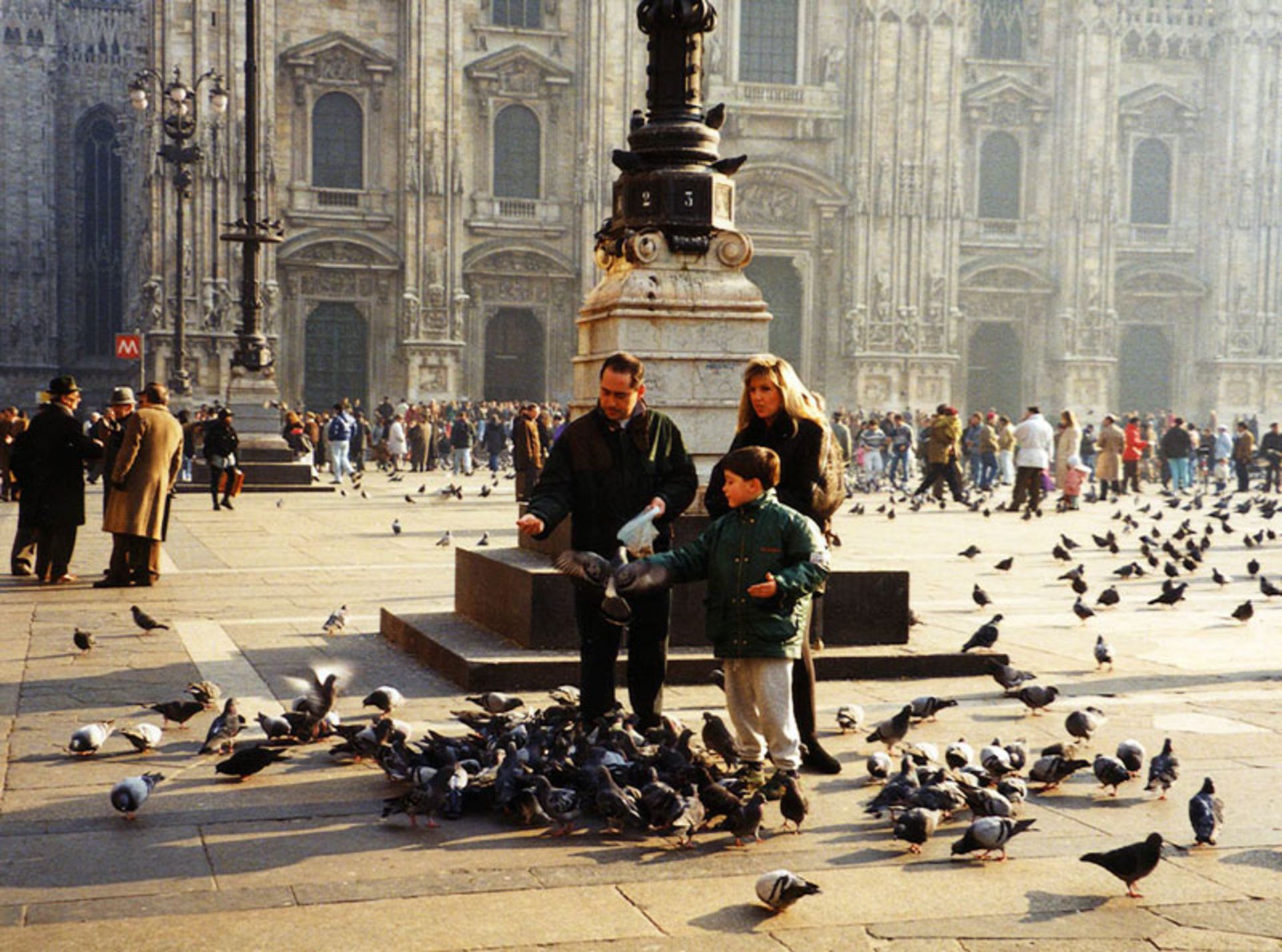 Man, woman and child feeding pigeons