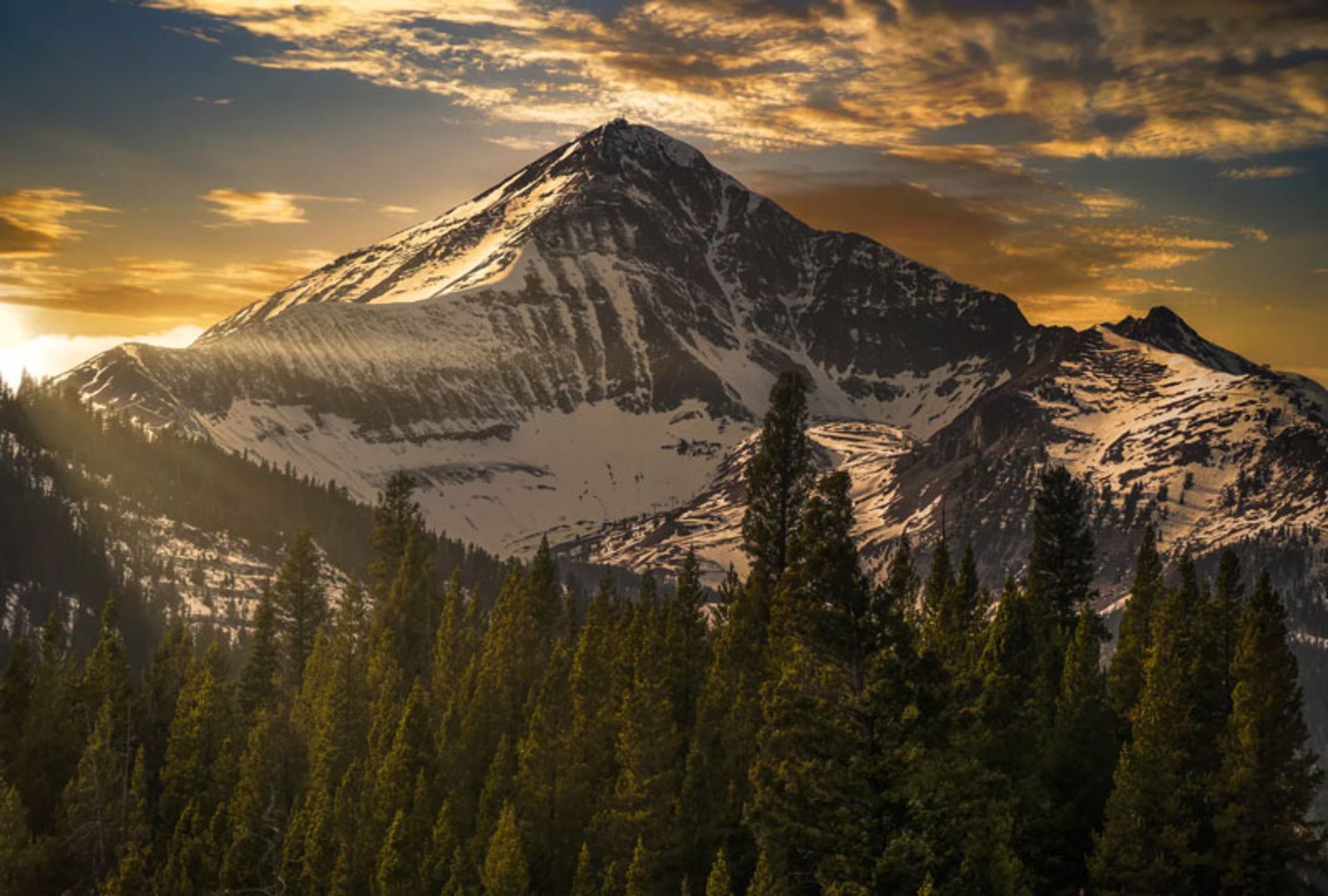 A golden sunset over a snow-capped peak in Moana's Big Sky