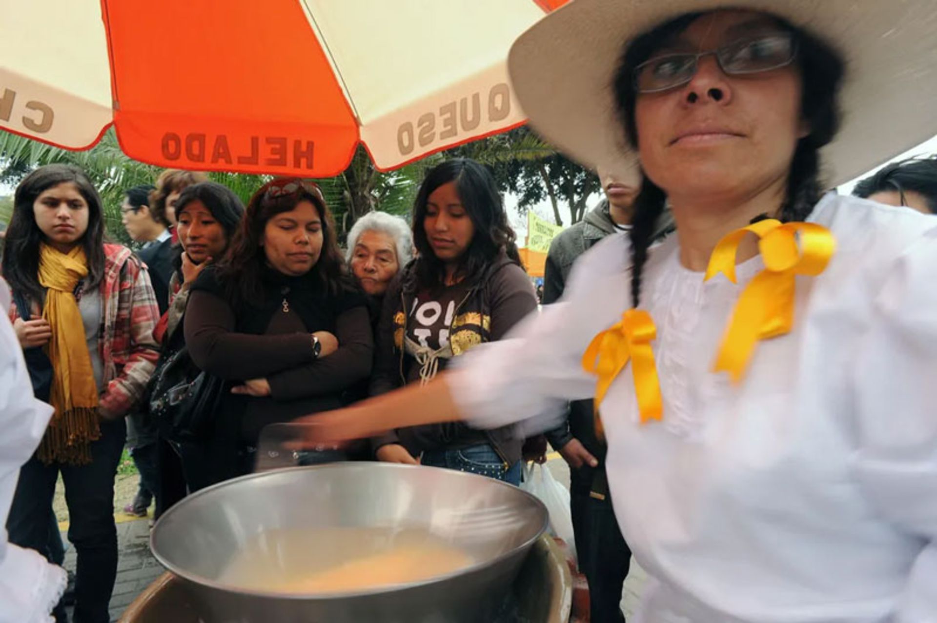 Peruvian women in traditional dress preparing frozen cheese dessert