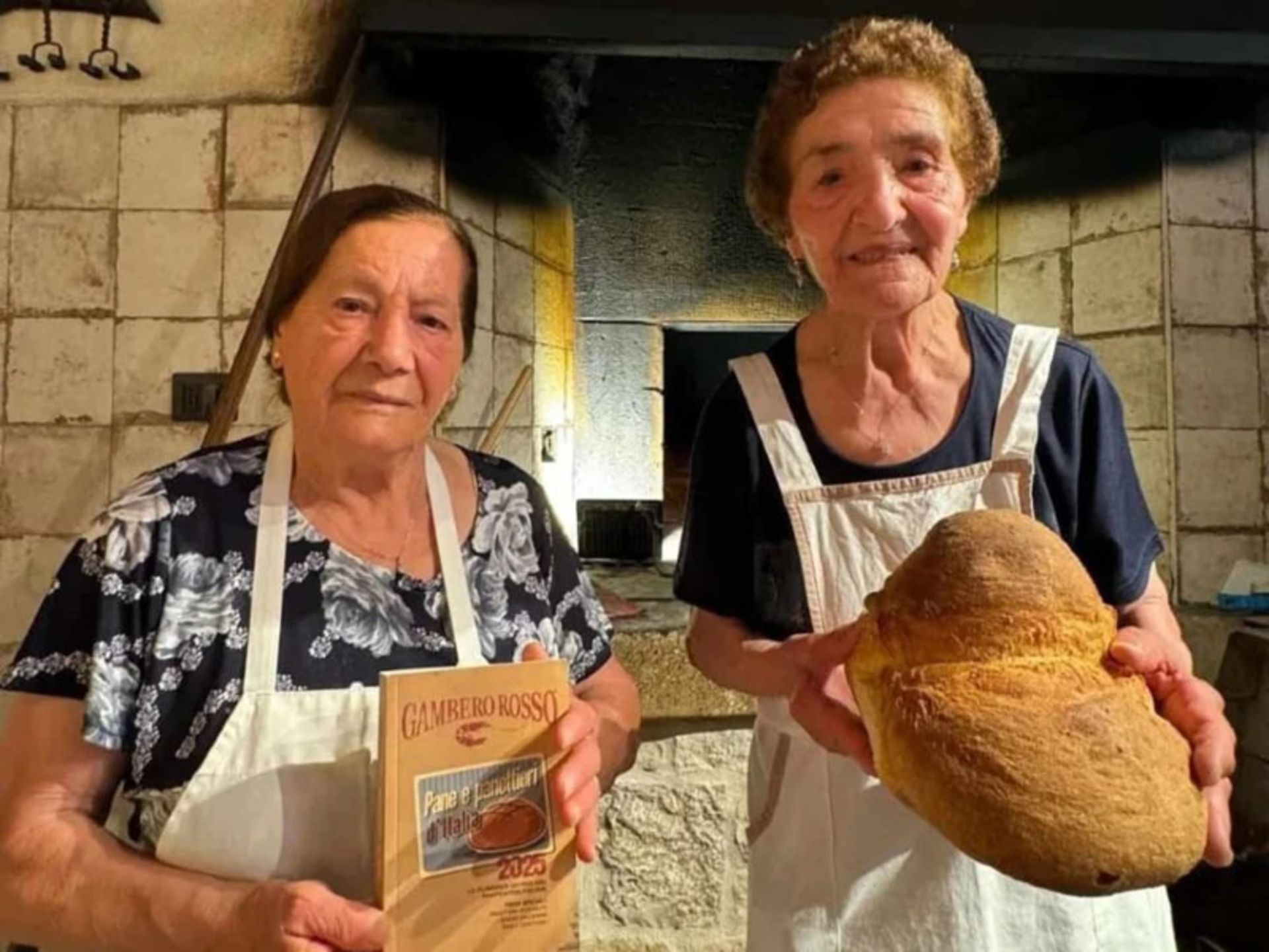 Two grandmothers in fro of an ancie wood oven