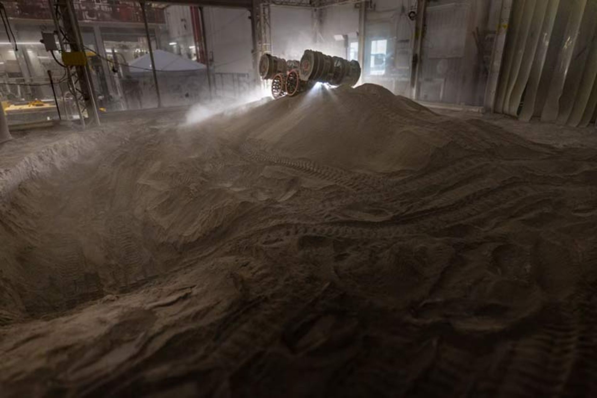 A rover experimeing with digging io a mound of simulated lunar soil 