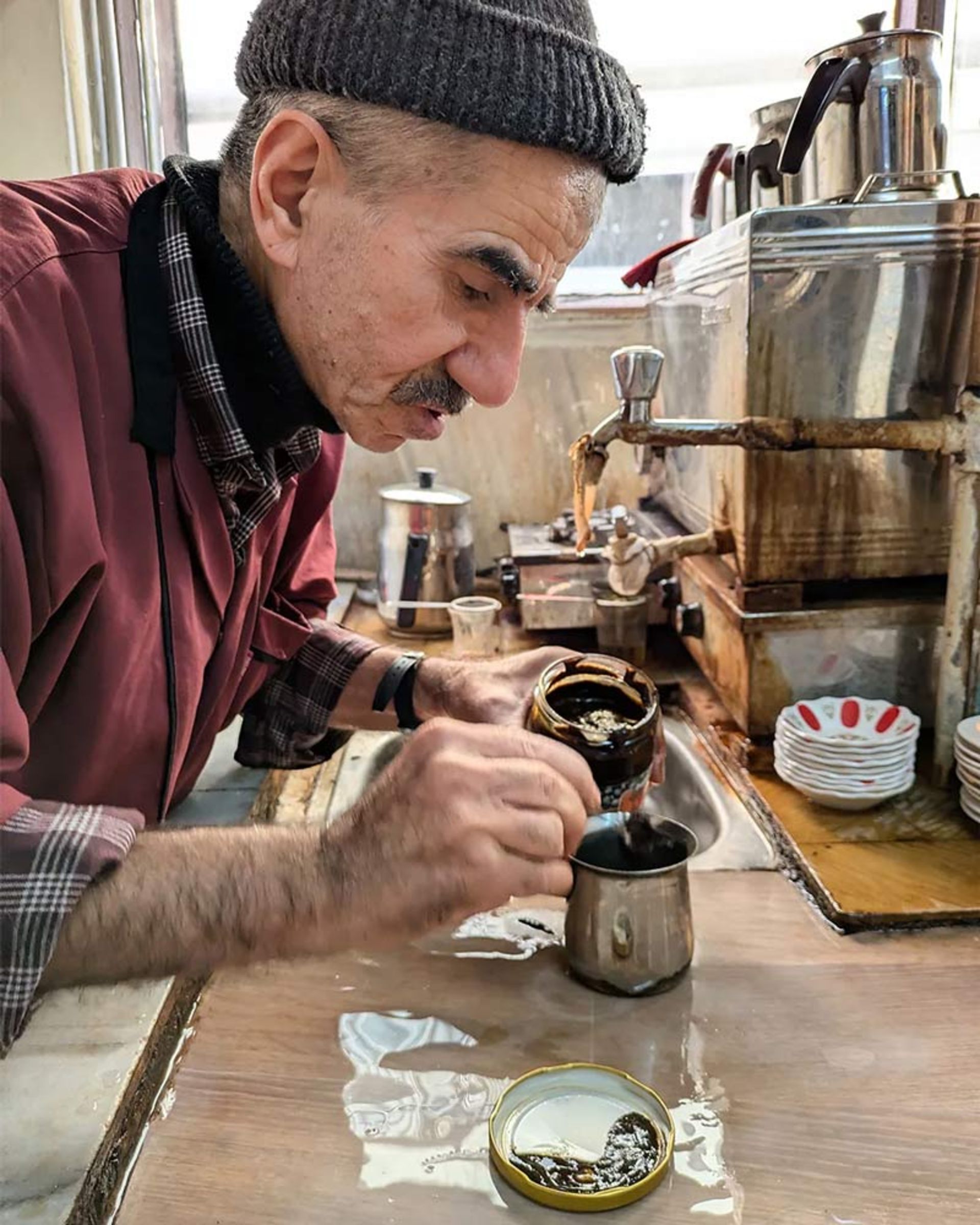 A coffee maker scooping up the thick Meningich paste with a spoon to prepare the drink