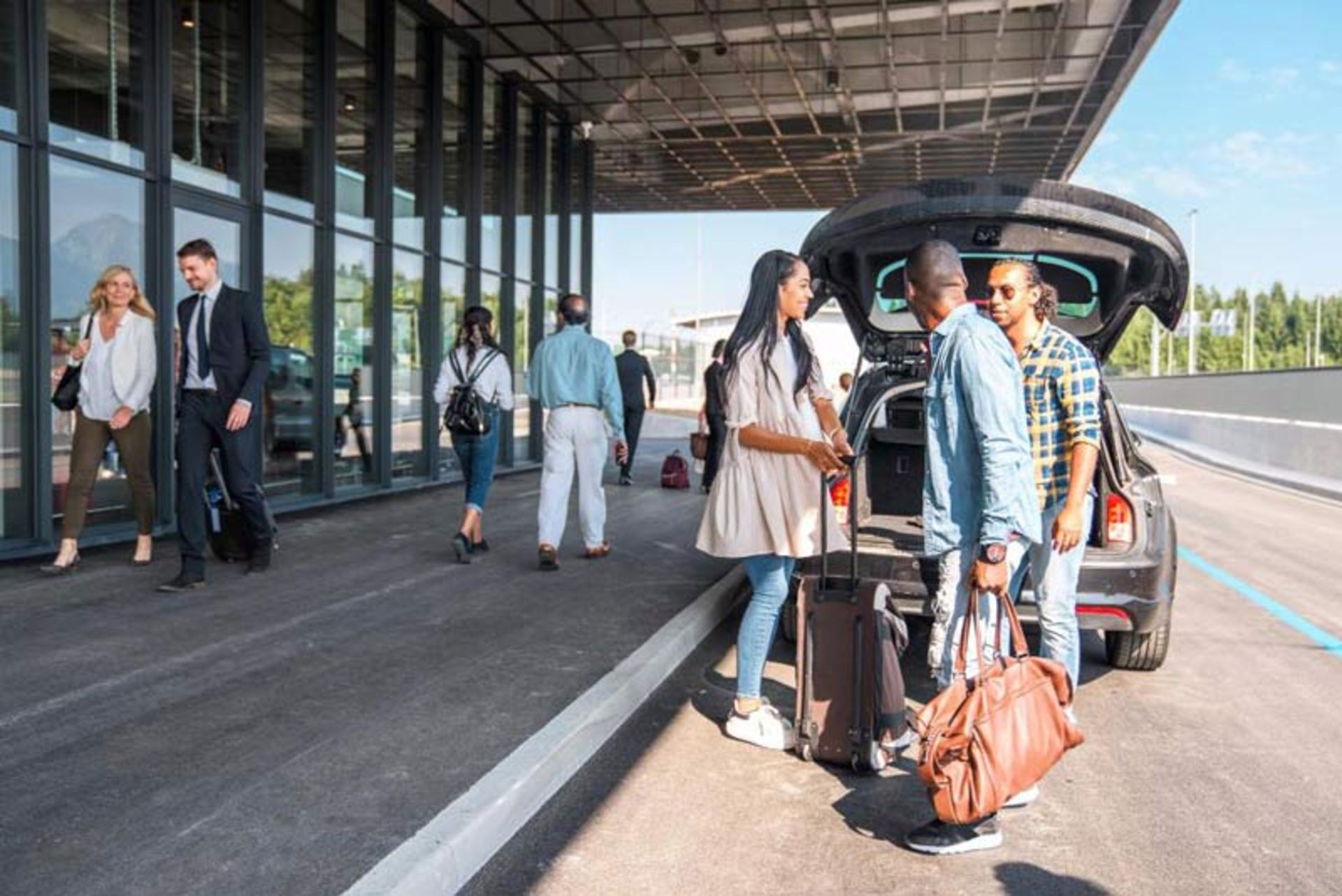 Removing the luggage from the trunk of the car in fro of the modern glass erance door of the airport