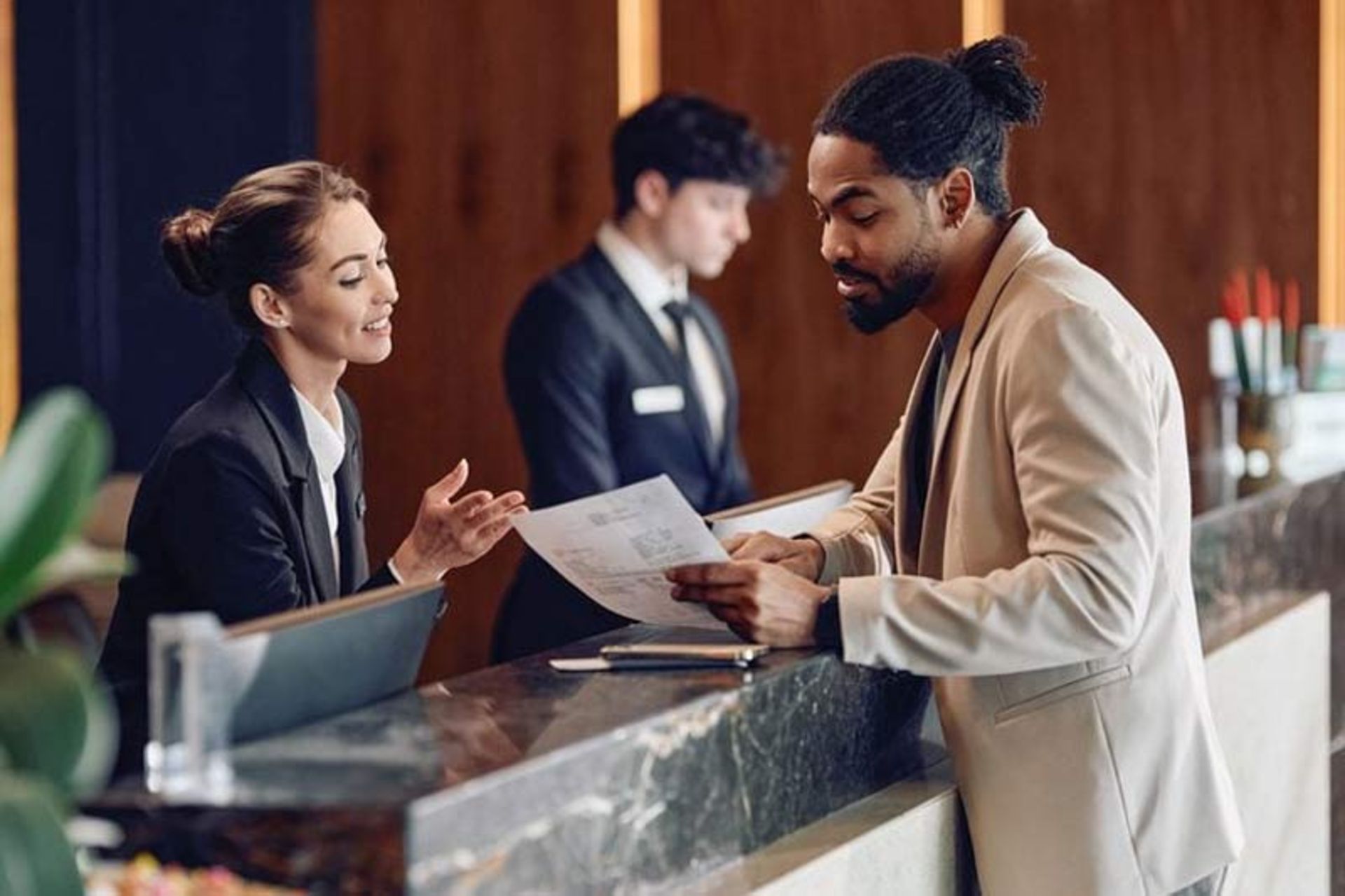 The traveler's conversation with the hotel reception staff in fro of the couer